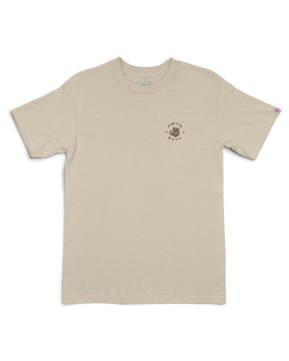 A light beige crewneck t-shirt with a small circular graphic on the left chest [sand]