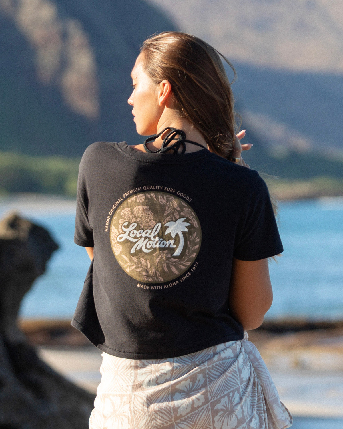 A woman viewed from behind wearing a black graphic t-shirt 