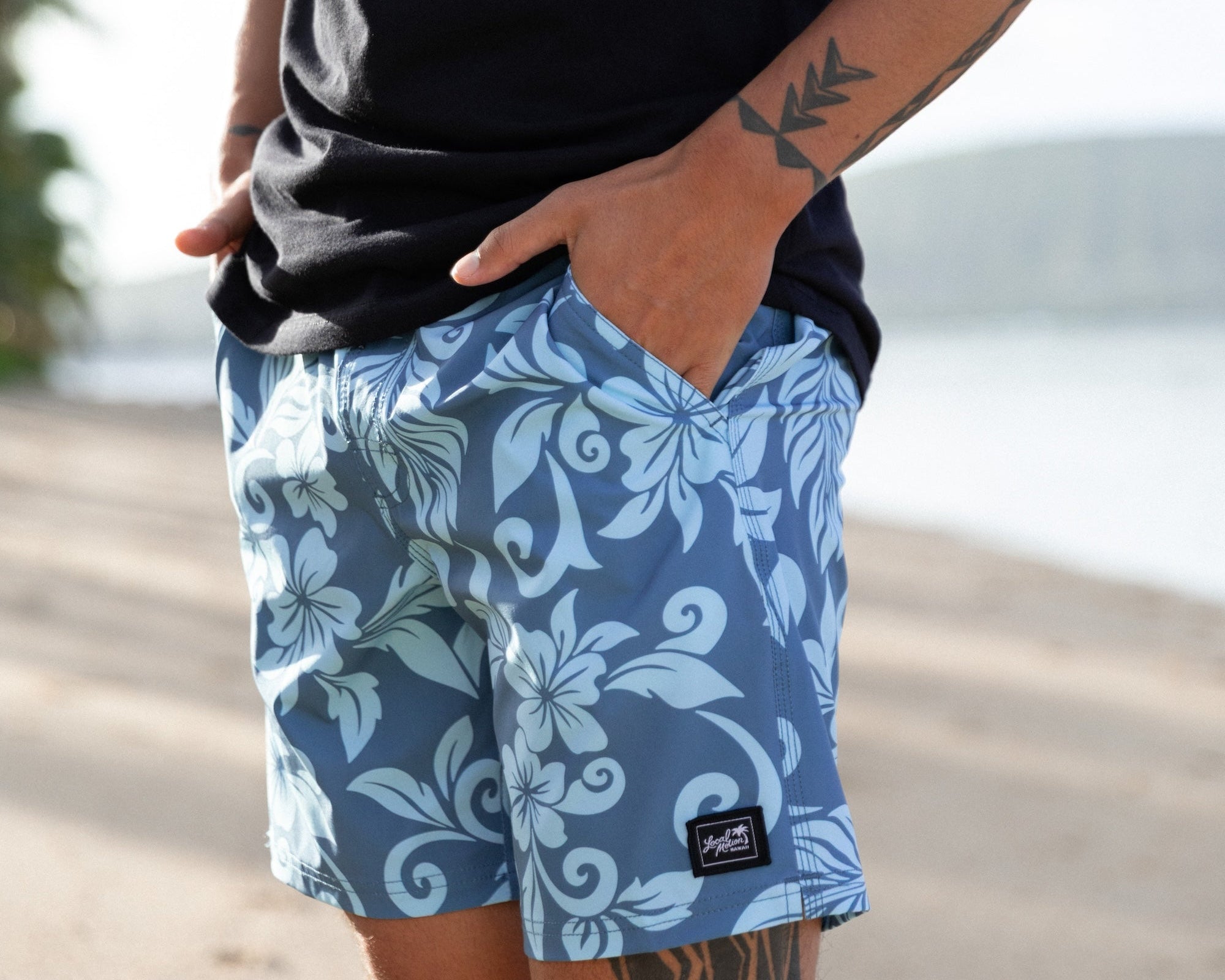 A man wearing blue and white floral patterned board shorts and a black t-shirt