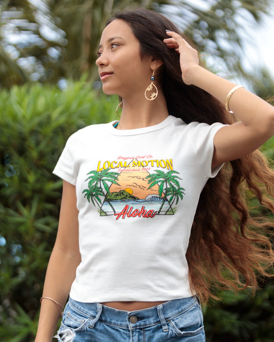 A woman wearing a white graphic t-shirt with a tropical sunset and palm tree design [vintage white]