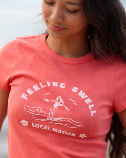 Woman wearing a red graphic shirt that reads 'FEELING SWELL' [rust red]