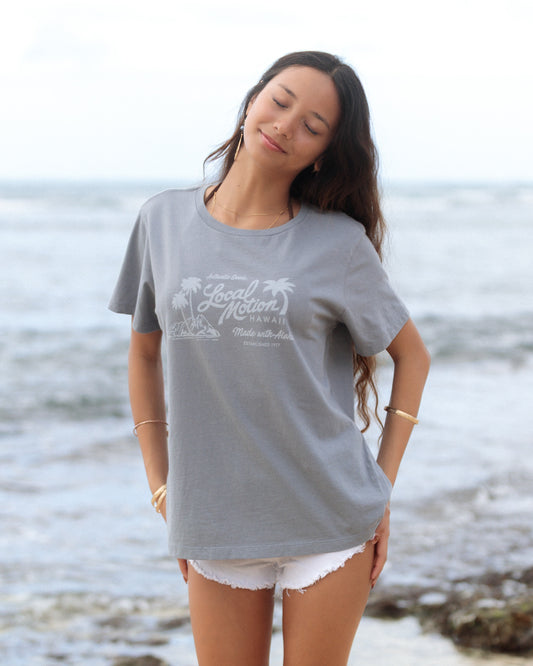 A woman standing on a beach wearing an oversized light gray graphic t-shirt [slate blue]