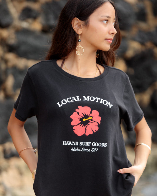 A woman wearing a black graphic t-shirt with a pink hibiscus flower [black]