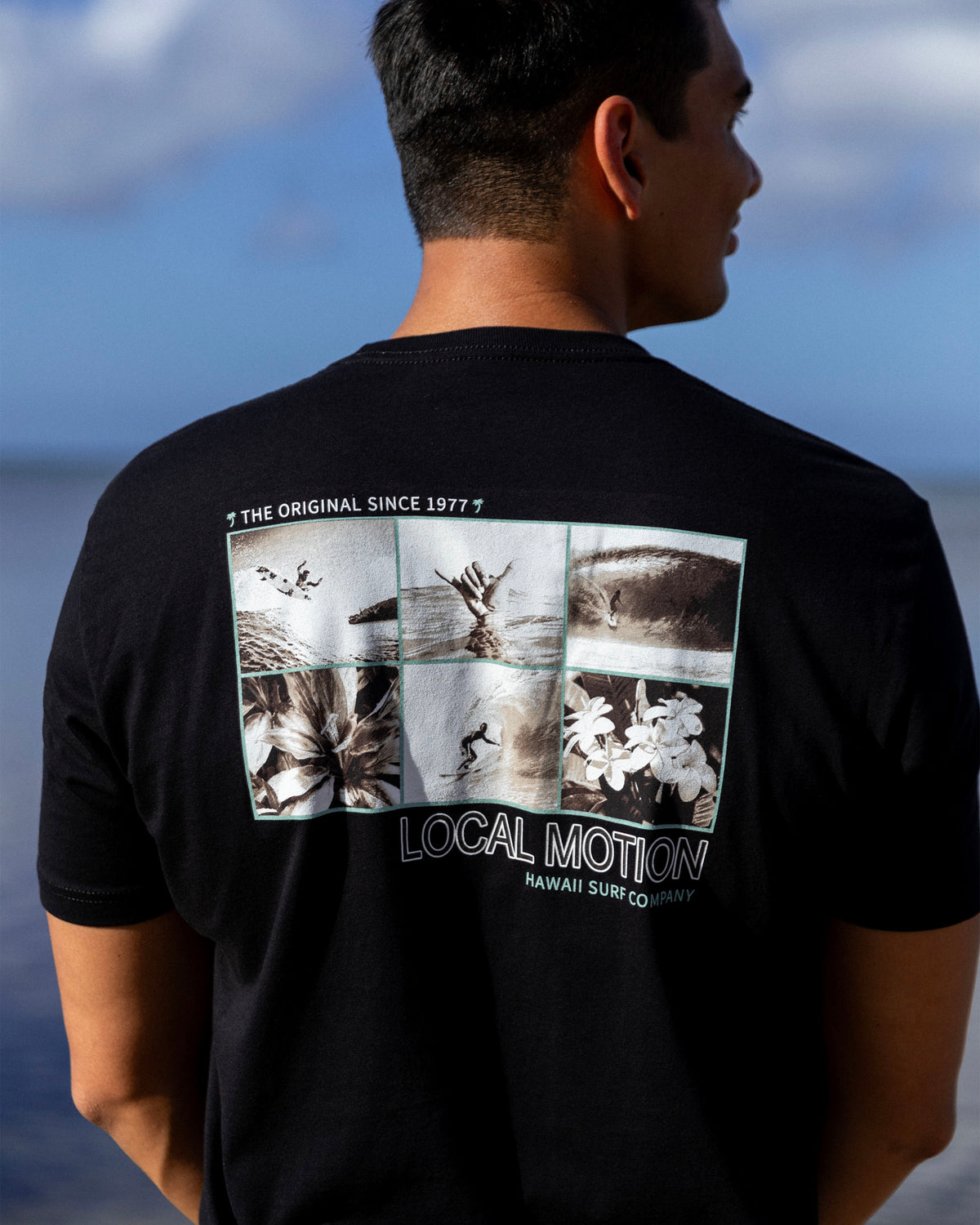 A man viewed from behind wearing a black t-shirt [black]