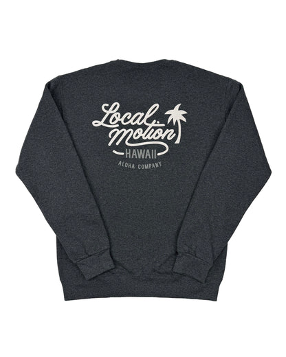 A dark heather gray crewneck sweatshirt shown from the back, featuring a white graphic print that reads 'Local Motion Hawaii Aloha Company' with a palm tree illustration.